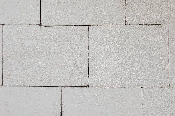 Close-up of a white painted brick wall with a rough textured surface and visible seams, ideal for backgrounds or architectural mockups.