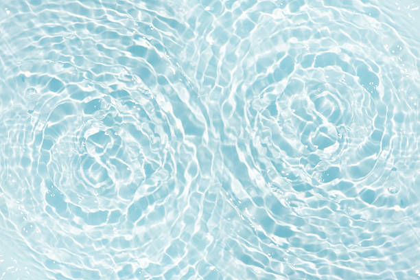 Blue water with ripples on the surface. Defocus blurred transparent blue colored clear calm water surface texture with splashes and bubbles. Water waves with shining pattern texture background.