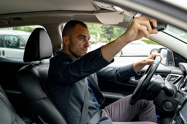 istock Businessman adjusting rearview mirror while driving car 2216267590