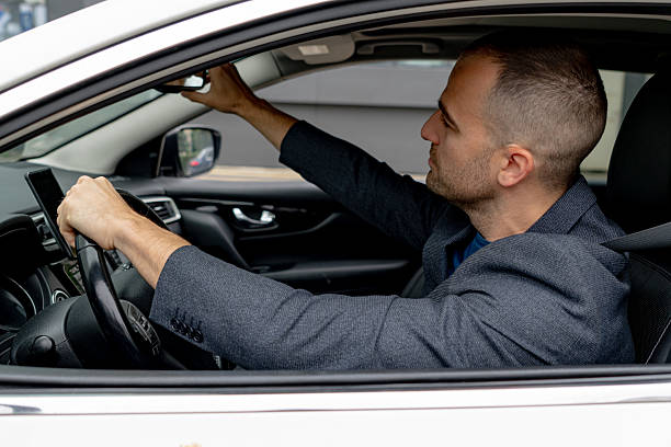 istock Businessman adjusting rearview mirror while driving car 2216267595