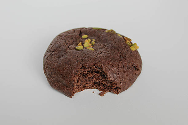 istock A bitten chocolate soft cookie, with green pistachio topping, isolated on white background 2216269782