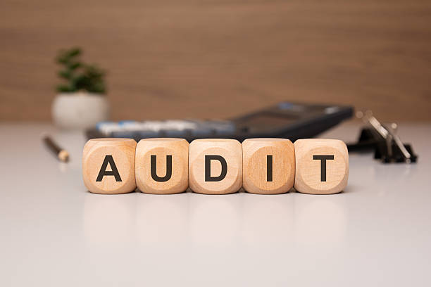istock Wooden blocks spelling AUDIT with office items in the background. 2216272314