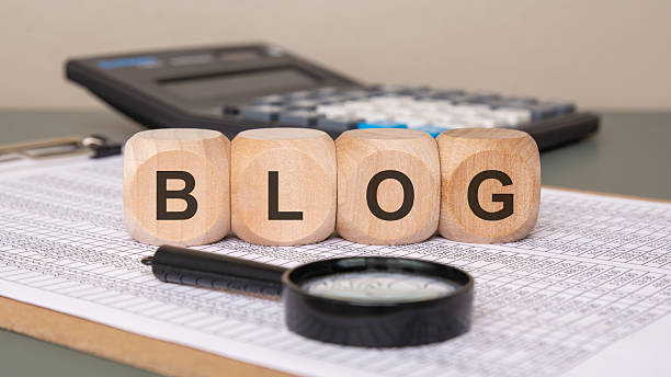 istock Wooden cubes spelling BLOG on financial documents. 2216272321