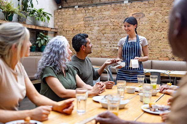 istock Waitress taking a mobile payment from a group of people at a restaurant 2216272947