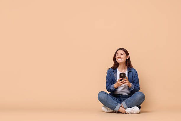 istock Smiling woman with smartphone on beige background. Space for text 2216274439