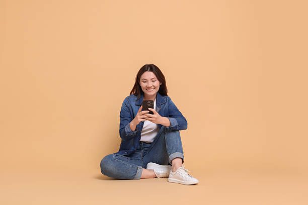 istock Smiling woman using smartphone on beige background 2216274517