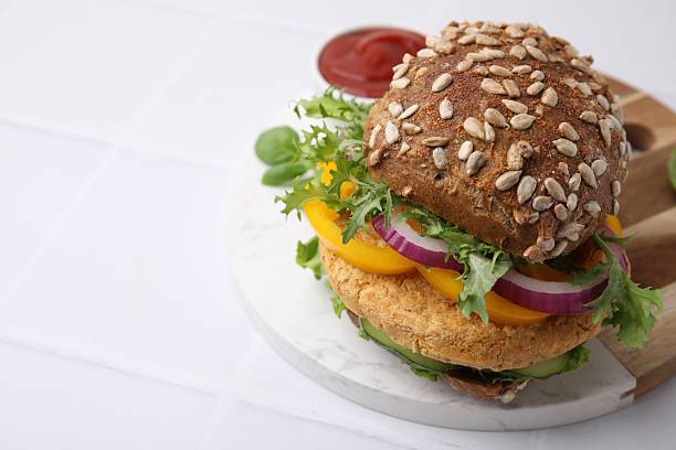istock Delicious vegan burger with chickpea cutlet on white tiled table, closeup. Space for text 2216275261