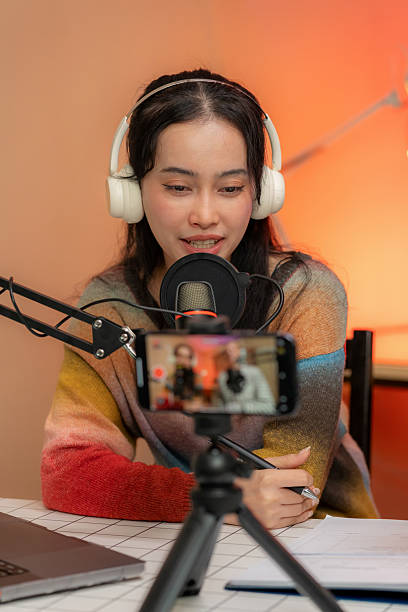 istock Confident female presenter sets up microphone and camera for live podcast streaming. In a modern recording studio, she showcases creativity, expertise, and technology in journalism, vlogging, and multimedia broadcasting. Real-time audience connection. 2216276932
