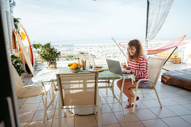 istock Smiling beautiful woman working while having breakfast on balcony at home 2216279721