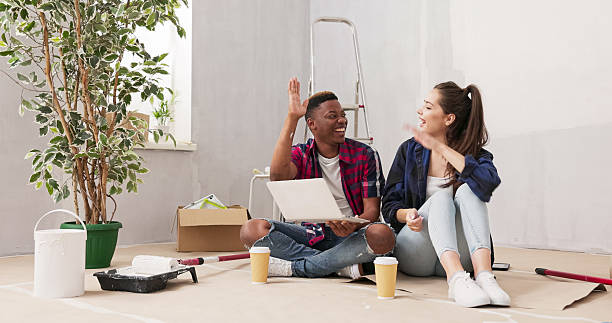 istock Lovers transform their new apartment, painting walls and exploring home decor ideas. Surrounded by tools, they browse inspirations on a laptop, order furniture, and high-five with joy. 2216280935