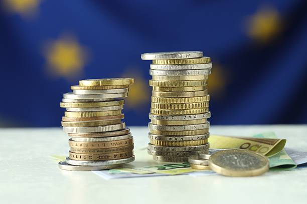 istock Stacks of coins and euro banknotes on white table, closeup 2216280948