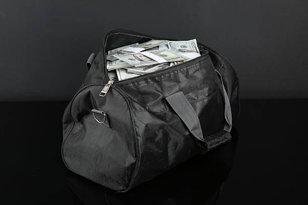 Dollar banknotes in bag on black mirror surface