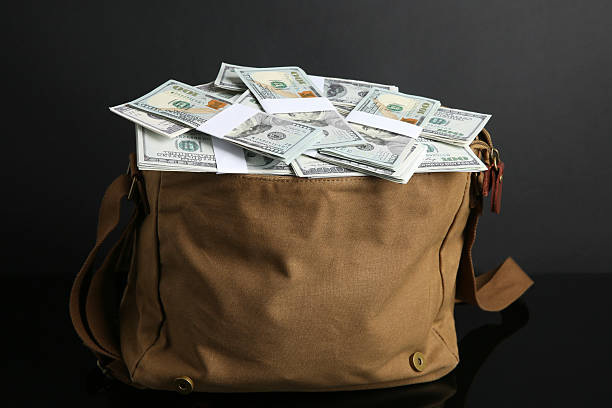 Dollar banknotes in bag on black mirror surface