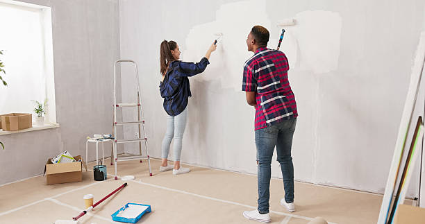 istock Two cheerful young friends renovate an apartment, holding paint rollers and playfully getting covered in white paint. Around them, boxes and a ladder create a lively renovation scene. 2216282121