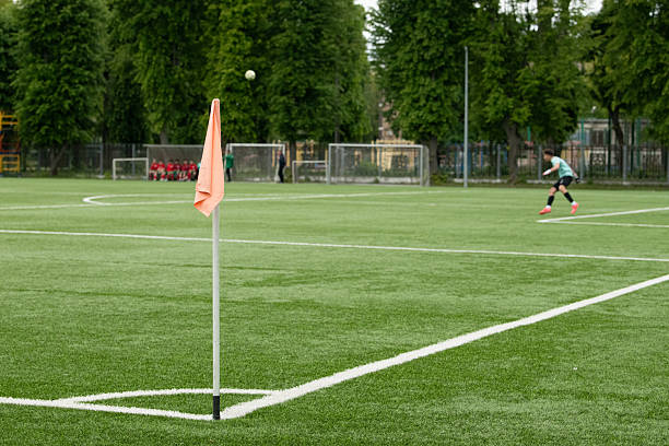 istock A soccer game is in progress on a well-maintained green field, featuring a player about to kick the ball near the corner flag while teammates observe from the sidelines 2216282658
