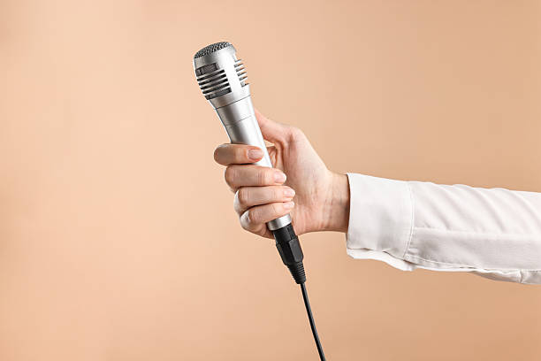 istock Woman with microphone on beige background, closeup 2216282787