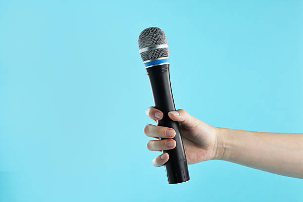 istock Woman with microphone on light blue background, closeup. Space for text 2216282831