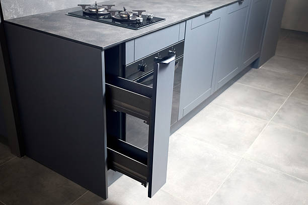 istock Vertical pull out rack cabinet drawer. Flush up slip handle finger pull handle of drawers for dishes, compact high pressure laminate HPL countertop, black glass gas stove cooker hob with two burners. 2216286040