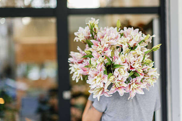 Florist is in front of her flower shop, holding a bouquet.