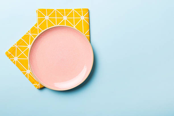 istock Top view on colored background empty round pink plate on tablecloth for food. Empty dish on napkin with space for your design 2216292724