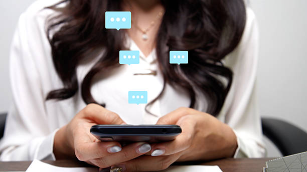 istock A person's hands hold a smartphone, with translucent speech bubbles layered above, suggesting a messaging or chat interface. The focus is on the interactive nature of mobile communication 2216293344