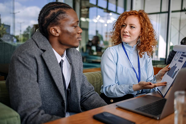 istock Businesswoman talking to a client at cafe while showing charts and using laptop 2216294590