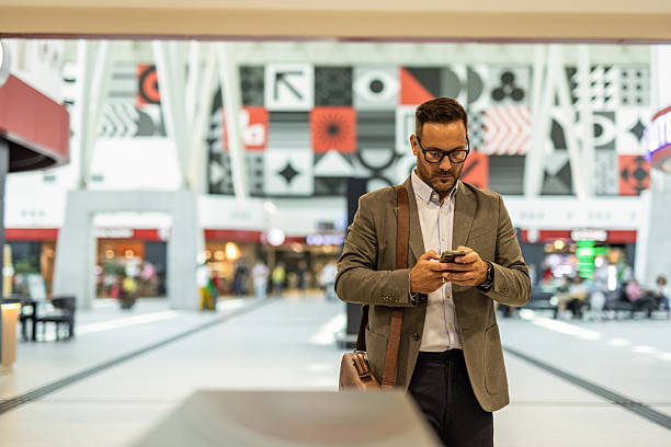 istock Businessman engaging with smartphone in modern airport 2216296031