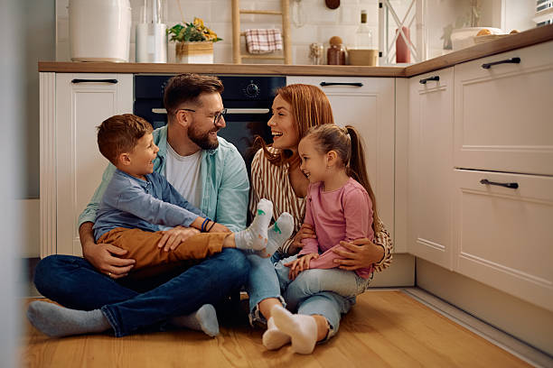 istock Cheerful parents and their kids talking while sitting on the floor at home. 2216296480