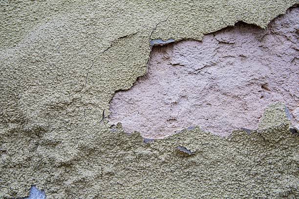 Close-up of a cracked, weathered concrete wall showing fractures and worn texture