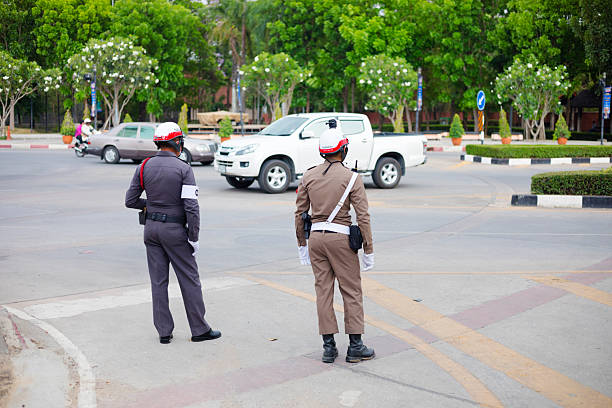 Ch, Thailand – January 27, 2022: A vertical shot of a policeman stopping traffic waving with baton. Thailand