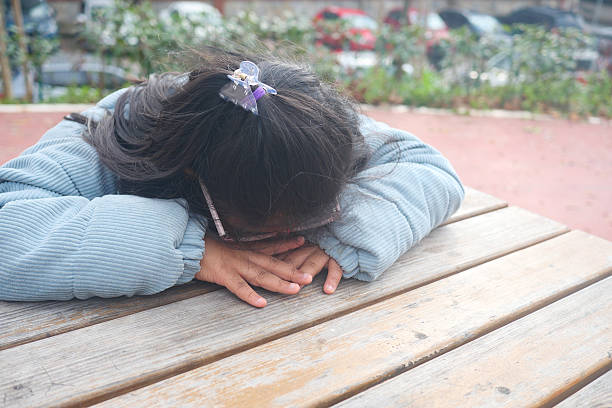 istock Child resting with head on table in a park during daytime 2216304381