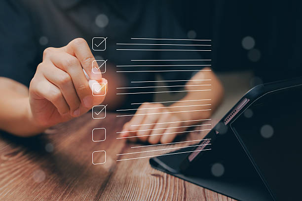 istock Hand Checking Off Tasks on a Digital Checklist with Tablet on Wooden Table Background 2216305626