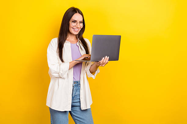 istock Photo portrait of attractive young woman hold netbook typing coder dressed stylish white clothes isolated on yellow color background 2216311205