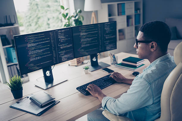 istock Close up side profile photo of professional young guy it specialist create code looking two modern monitors typing keyboard stay in office 2216312472