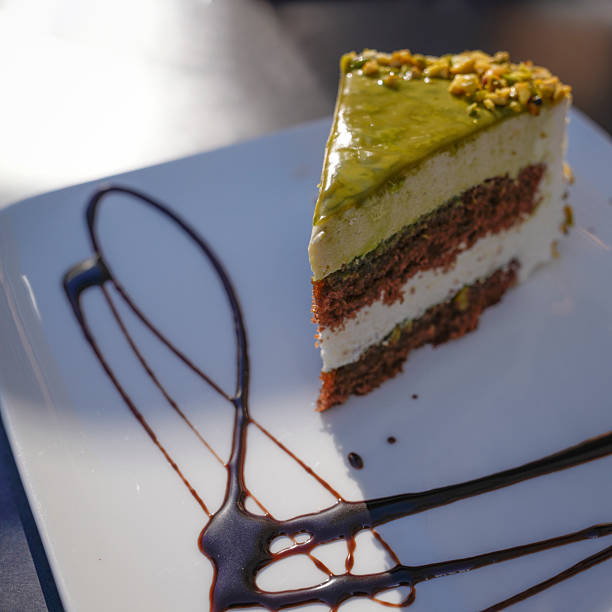 A beautiful piece of chocolate pistachio cake on a chocolate decorated plate