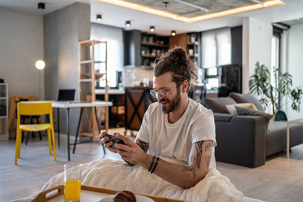 istock Young man playing mobile games in bed after waking up 2216319004