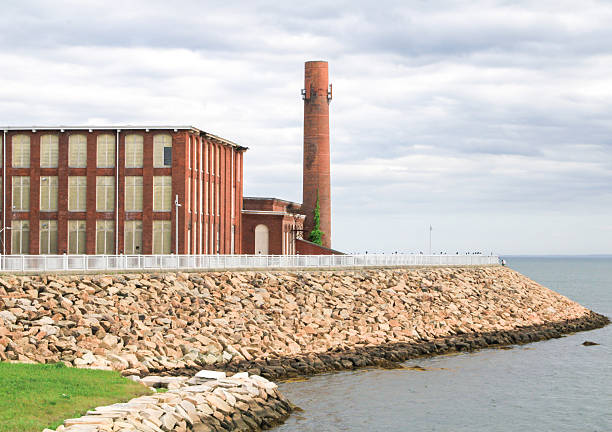 The imposing New Bedford Hurricane Barrier, a testament to mid-20th century engineering, provides a protective embrace to New Bedford Harbor. Its elevated walkway, known as CoveWalk, allows visitors to experience this significant coastal defense structure firsthand while offering sweeping vistas of the surrounding coastline, including views of abandoned mills and factories, and the broader expanse of Buzzards Bay. A powerful visual representation of human ingenuity safeguarding a historic maritime city.