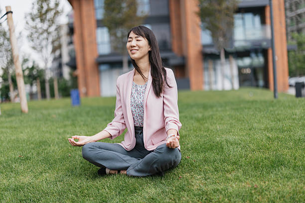 istock Woman meditating peacefully on green grass area 2216327751