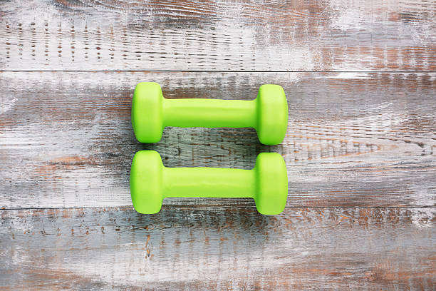 istock Green dumbbells on grey wooden table 2216333785