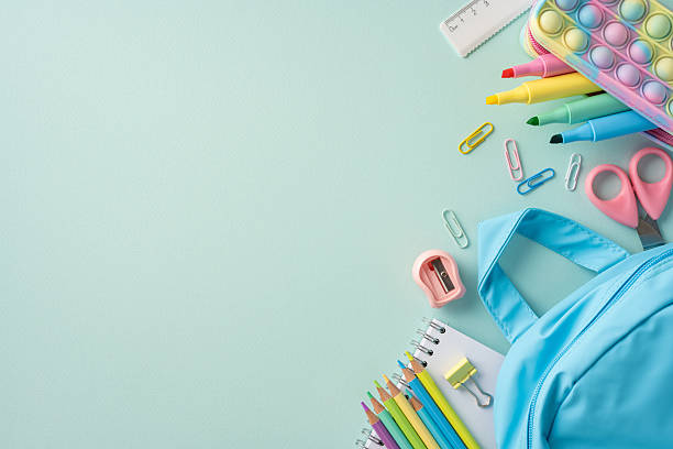 istock Colorful school supplies alongside a light blue backpack arranged on a green backdrop 2216334900