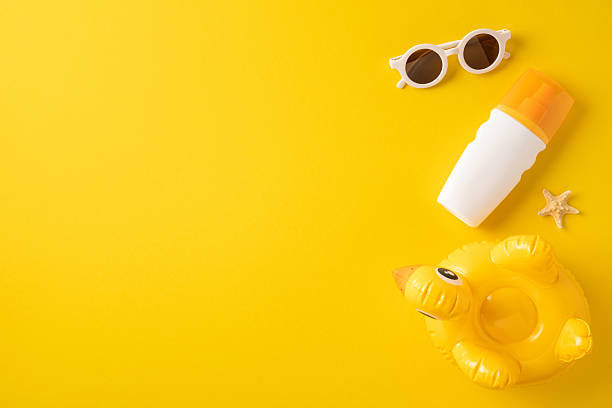 istock Flat lay composition of sunglasses, sunscreen bottle, inflatable duck float, and starfish on yellow 2216334958