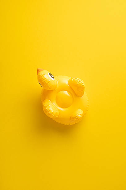 istock Bright vertical yellow inflatable duck toy featured on a bold yellow backdrop conveying summer vibes 2216334979