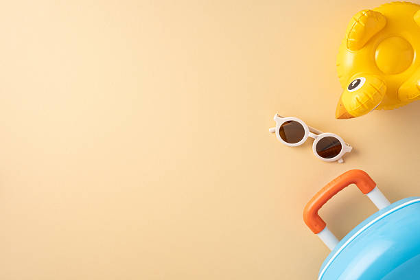istock Travel items including sunglasses, an inflatable duck float, and a suitcase on light background 2216334982