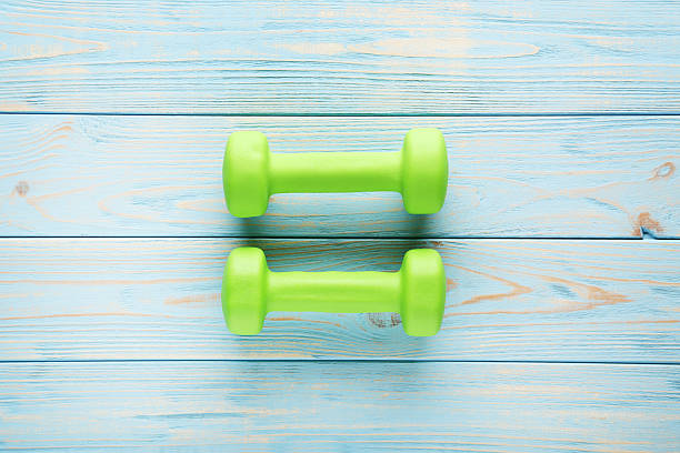 istock Green dumbbells on blue wooden table 2216335040