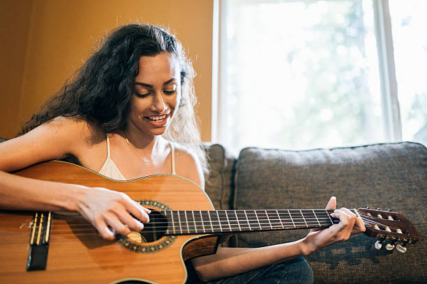 istock Woman Playing Classical Guitar on Sofa 2216335707