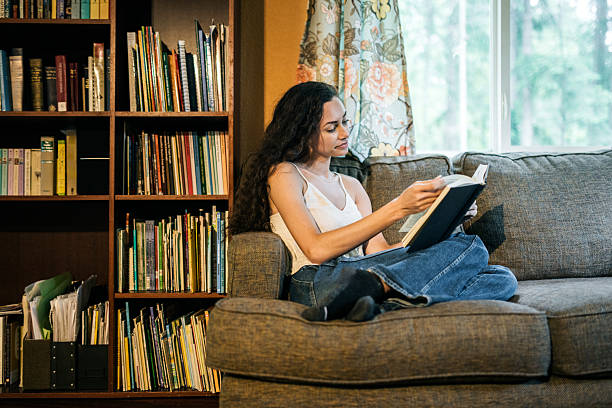 istock Women Relaxes in Comfortable Chair With Novel 2216335710