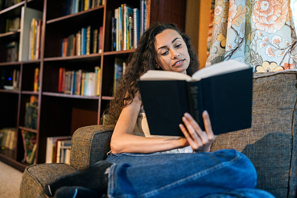 istock Women Relaxes in Comfortable Chair With Novel 2216335765
