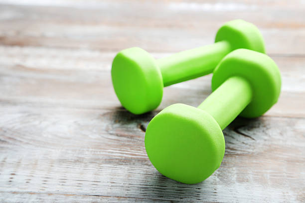 istock Green dumbbells on grey wooden table 2216336637
