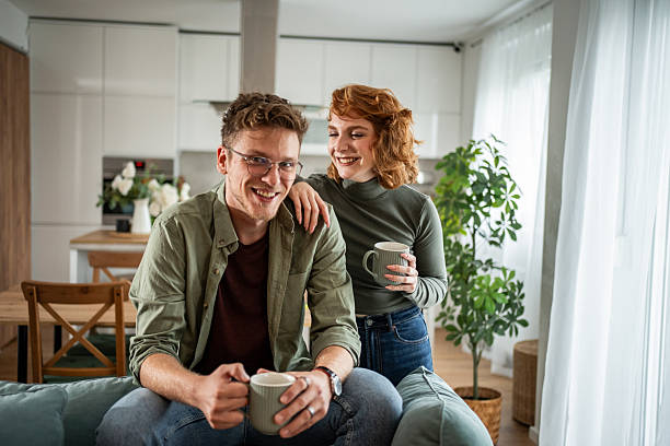 istock Young couple smiling and drinking coffee on sofa at home 2216339730