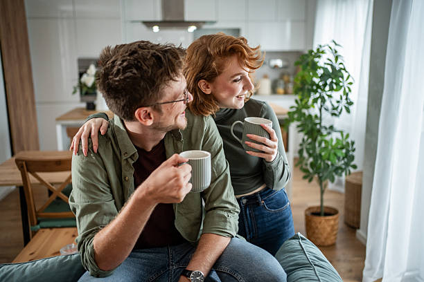 istock Young couple relaxing on sofa, enjoying morning coffee and conversation 2216339758